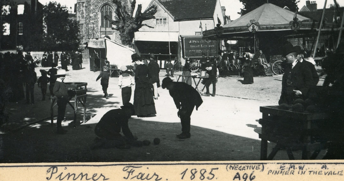 Pinner Fair 1885, two children playing balls and market stalls in the background / black and white image